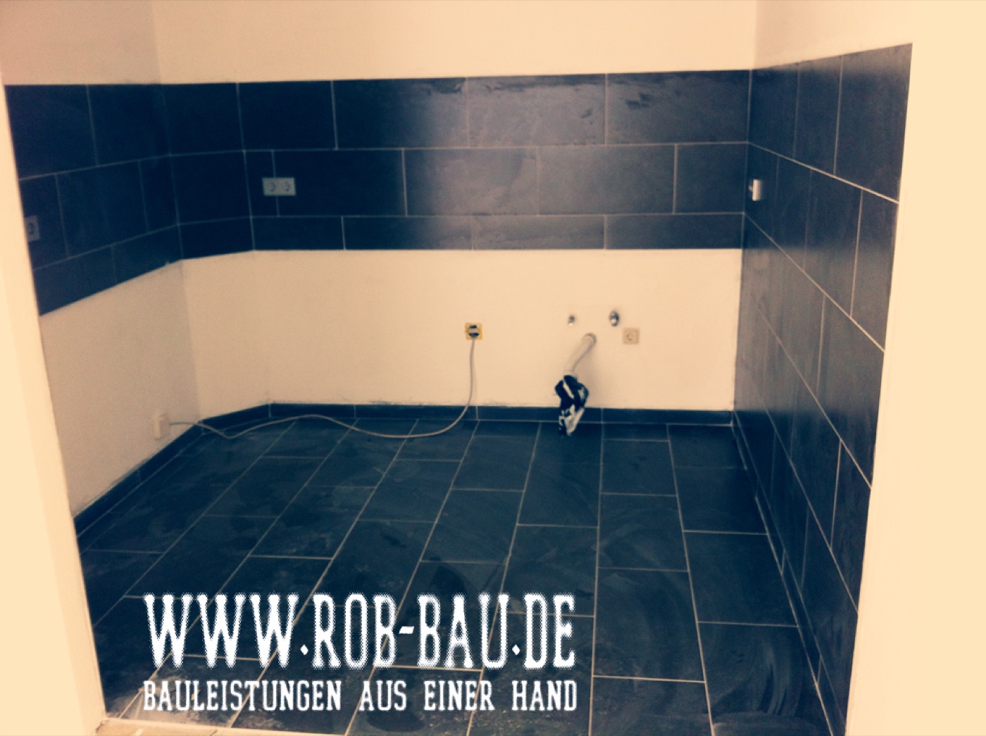 Badrenovierung mit dunklen Wand- und Bodenfliesen